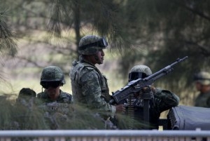 Soldados del ejército mexicano vigilan la zona cerca de la entrada de la finca Rancho del Sol, en el municipio de Ecuandureo, estado de Michoacán, en el oeste de México, el viernes 22 de mayo de 2015, tras un enfrentamiento en el lugar entre presuntos miembros de un cartel narcotraficante y fuerzas del orden. La confrontación, que duró tres horas, es la más cruenta de su tipo ocurrida en fecha reciente en el país y según autoridades, en el lugar murieron 42 supuestos delincuentes y un policía federal. (AP Foto/Eduardo Verdugo)