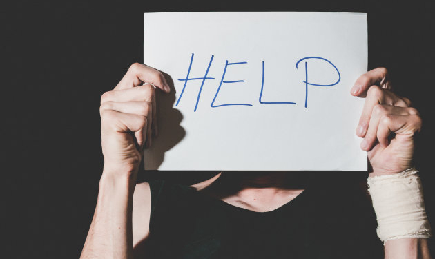 Help. Suicidal depression. Man holding help sign paper. Black background. dark image.