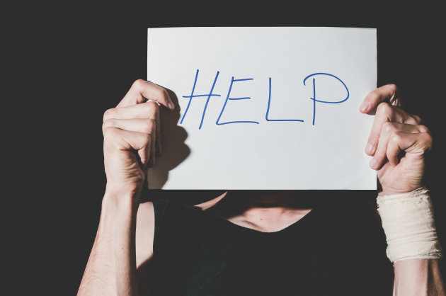 Help. Suicidal depression. Man holding help sign paper. Black background. dark image.