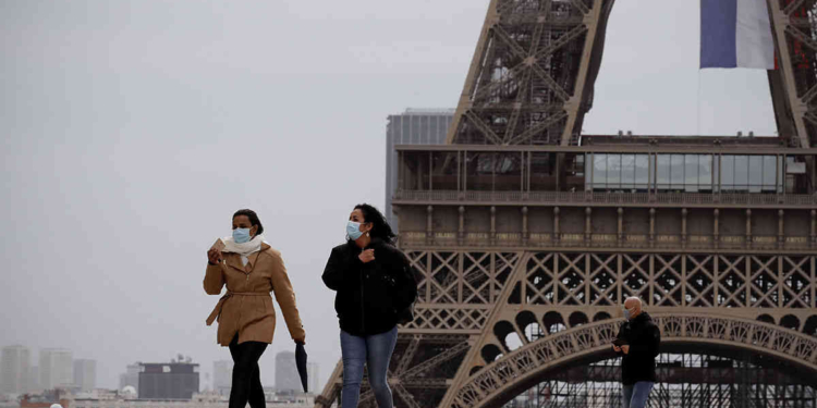 People walk near the Eiffel Tower, in Paris, Monday, May 11, 2020. The French began leaving their homes and apartments for the first time in two months without permission slips as the country cautiously lifted its lockdown. Clothing stores, coiffures and other businesses large and small were reopening on Monday with strict precautions to keep the coronavirus at bay. (AP Photo/Christophe Ena)